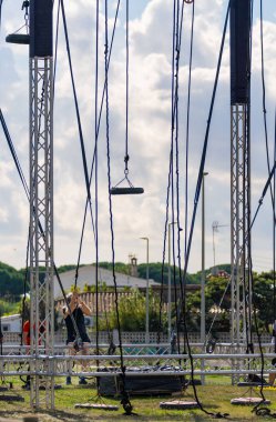 Kıdemli sporcu, parkta bir engelli parkurunda lastiğin ağırlığını kaldırmak için sallanan ipi itiyor..