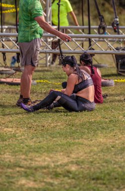 Bir sporcu arkadaşı, çimlerin üzerinde oturan bayan sporcuyu yoğun bir engelli koşusundan sonra üzerine su atarak tazeler..