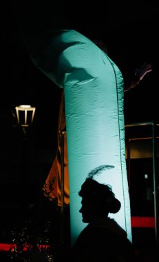 Bilge Adam 'ın silueti, Üç Krallar Günü geçit töreninde gece boyunca parlak renkli fenerlerin yanında tüylü bir şapka takıyor..