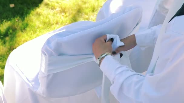 Vrouw versiert bruiloft stoel met wit lint — Stockvideo