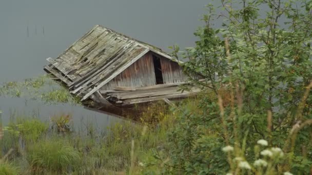 Starý vratký dřevěný dům ve vodě na břehu jezera v Karelii, Rusko. — Stock video