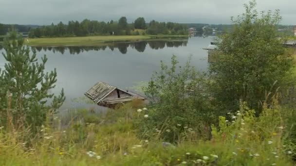 Starý vratký dřevěný dům ve vodě na břehu jezera v ruské Karelii. V pohybu. — Stock video