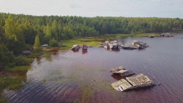 Вид с воздуха на берег озера в Карелии с затонувшими наклонными домами в воде, Россия. — стоковое видео