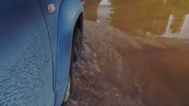 View of a wheel passing through a long puddle from the window of a moving car. Dirt road in Karelia, Russia. — Stock Video