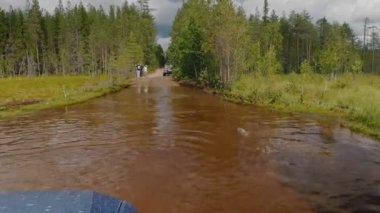 Uzun bir su birikintisinden geçen bir arabanın penceresinden bak. Karelia, Rusya 'da toprak yol.