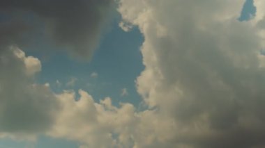 Kalın beyaz bulutlar mavi yaz gökyüzünde süzülür. Zaman ayarlı. Güneşli.