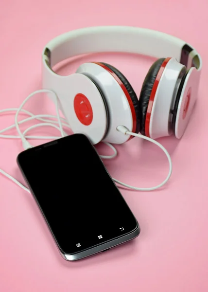 Headfones e smartphone em fundo rosa . — Fotografia de Stock