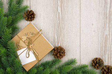 İçinde geyik olan yeni yıl hediyesi kutusu, tahta bir arka planda ağaç dalı. Metin için yeri olan pankart. Kırsal arka plan. Noel ağacı dalları olan eski ahşap döşeme. Düz. Üst yaşam