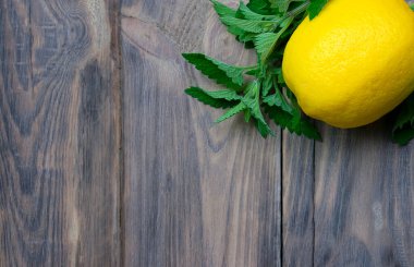 Limon ve nane, yakın plan. Tahta bir masanın üzerindeki turunçgil. Vitaminler. Dokunulmazlık. Alternatif tıp kavramını ele alalım. Soğuk algınlığı ve grip için doğal ev yapımı ilaç. Bağışıklık sistemini destekleyin. Refah ve Sağlık.