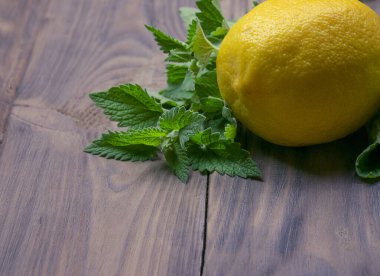 Limon ve nane, yakın plan. Tahta bir masanın üzerindeki turunçgil. Vitaminler. Dokunulmazlık. Alternatif tıp kavramını ele alalım. Soğuk algınlığı ve grip için doğal ev yapımı ilaç. Bağışıklık sistemini destekleyin. Refah ve Sağlık.