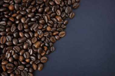 Ahşap arka planda kahve çekirdekleri ile kavrulmuş kahve fincanı ve ahşap masaya dağılmış kahve çekirdekleri. Taze kahve çekirdekleri. Kahve çekirdekleri..