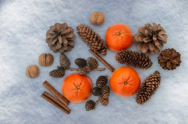 Mandalina, tarçın çubukları, fındık, karda çam kozalakları. Kış tatilinin lezzetleri. Noel havası yaratmak için doğal dekorasyonlar. Üst görünüm, düzlük, kopyalama alanı 
