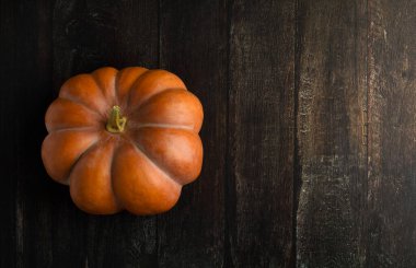 Masanın üstünde turuncu balkabağı var. Sonbahar arkaplanı. Sağlıklı gıda konsepti. Kabak kabağı maketi. Üst Manzara. Düz yatıyordu. Koyu arkaplan.