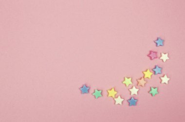 Pembe arka plana serpilmiş minyatür yıldızların büyüleyici bir görüntüsü.