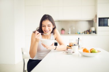 Young smiling woman eating cereal and smiling.Healthy breakfast.Starting your day.Dieting,fitness and wellbeing.Positive energy and emotion.Productivity,happiness,enjoyment concept.