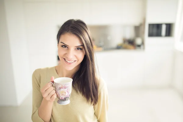 Mujer joven disfrutando, sosteniendo la taza de bebida caliente, café o té a la luz del sol de la mañana.Disfrutando de su café de la mañana en la cocina.Aprovechando una taza de café respirando el aroma —  Fotos de Stock