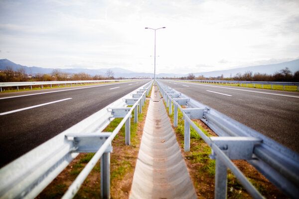 Freeway on a sunny day trough scenic green meadows.Motorway traveling long distance.Asphalt highways road in rural scene use land transport and traveling concept.