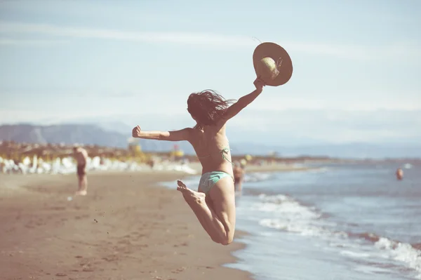 Donna che salta in aria sulla spiaggia tropicale, divertendosi e celebrando l'estate, bella donna giocosa che salta di felicità — Foto Stock