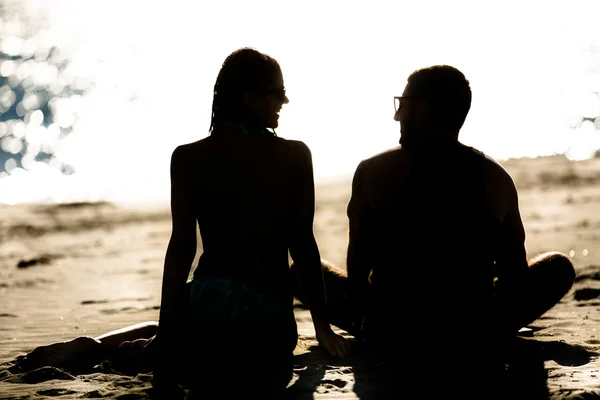 Silhuett av ett par i kärlek på stranden vid solnedgången. Kärlekshistoria. Man och en kvinna på stranden. Vackra par i solljus — Stockfoto