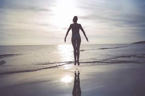 Mujer despreocupada bailando en la puesta de sol en la playa.Vacaciones vitalidad concepto de vida saludable . — Foto de Stock