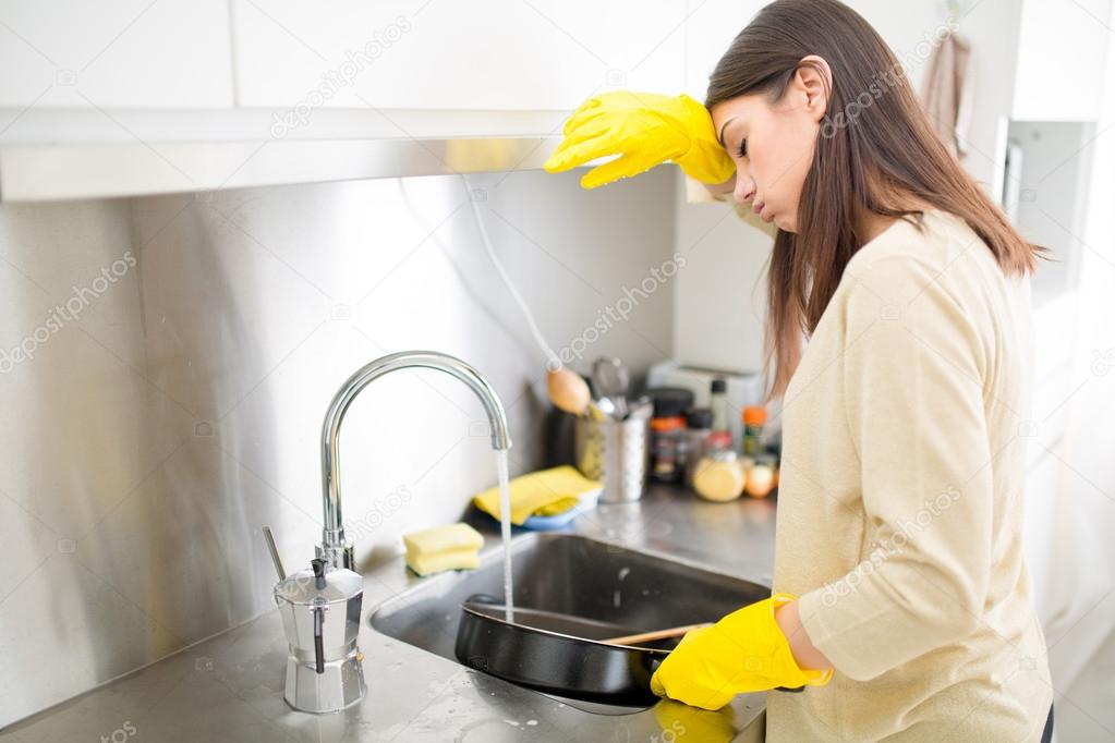 Hand cleaning.Young housewife woman washing dishes in kitchen.Young brunette woman washing dishes manually.Tired of cleaning