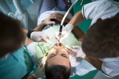 Male middle age patient in the dental clinic with the dentist doctor and nurse / assistant. Middle aged man fixing teeth in dental clinic