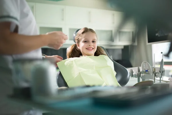Holčička má zuby vyšetřit zubaře. Malá holka sedí a usmívá se v kanceláři zubařů. Dítě strach ze zubaře — Stock fotografie