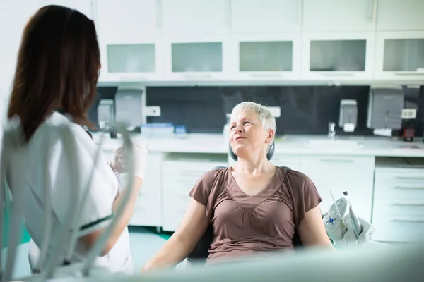 Yaşlı kadın onun diş bakımı diş hekimi ziyaret etti. Diş hekimi doktor bir kadın kıdemli hastayla konuşuyor. Yaşlı için diş bakımı