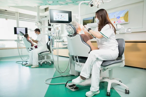 Moderne tandheelkundige kliniek met twee tandheelkundige stoelen, tandarts artsen werken met geduld, werken in de stomatologie kliniek met tandheelkundige medische apparatuur. — Stockfoto