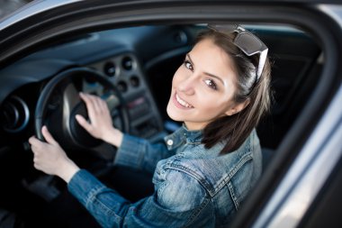 Yeni araba, kapalı mutlu kadın etrafında dönen, gülümseyen tekerleği tutar. Genç kadın arabada yol geziye gidiyor. Öğrenci sürücü öğrenci sürüş araba. Sürücü lisans sınavı. Kadın paylaşım araba kullanma.