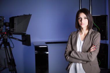 Young beautiful brunette television announcer at studio standing next to the camera.TV director at editor in studio clipart