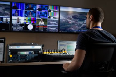 Stüdyoda editörde televizyon mühendisi. Televizyon editörü bir televizyon yayın galerisinde vizyon karıştırıcı ile çalışıyor. Adam bir vizyon karıştırma bölmesi oturdu