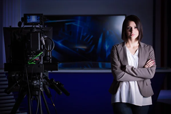 Unga vackra brunett TV hallåman på studio står bredvid kameran. TV-chef på editor i studio — Stockfoto