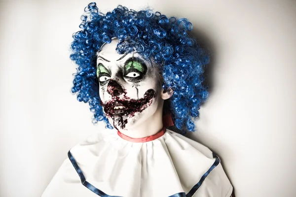 Eine Großaufnahme eines gruseligen Clowns mit scharfen spitzen Zähnen, der einen anstarrt. Crazy ugly grunge evil clown an halloween — Stockfoto