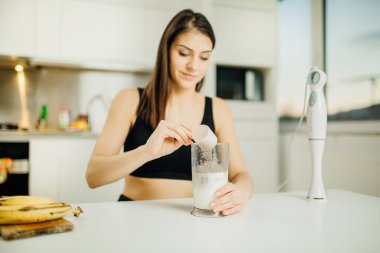Dalış blendırlı bir kadın muzlu çikolatalı protein tozu yapıyor, milkshake yapıyor. Spor salonundan sonra sallamak için düşük karbonhidratlı süt karışımı. Sağlıklı yaşam tarzı.