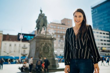 Gülümseyerek Hırvatistan 'ın Zagreb kentini ziyaret eden heyecanlı bir bayan turist görülüyor. Şehir merkezinde yürüyüş turu gezisi. Hırvat başkenti turizmi. Kültür, tarihi yerleri ve turistik yerleri keşfetmek. Avrupa 'da Tatil