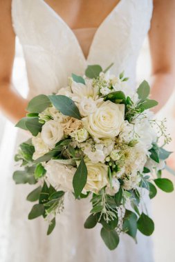 Geleneksel açık pembe ve beyaz güller bir gelin buketinde sergileniyor. Dantelli gelinlik içinde düğün töreni için zarif bir buket çiçek tutan romantik bir kutlama süsü..