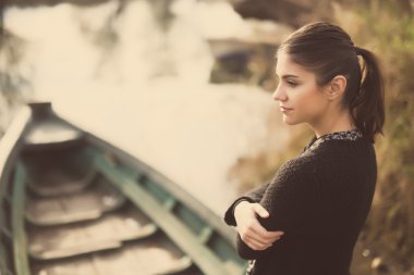Girl at the old fishing boat looking to the lake.Melancholia sadness sorrow concept.