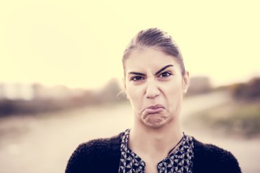 Cheeky woman mocking in a playful humorous joke.Negative human emotion facial expression.Young pretty woman with funny face mocking someone.Young pretty woman with funny face