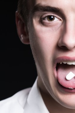 Drugs abuse and addiction tablets.Drug abuse,health danger.Young man under drug influence.Adolescent taking drugs for fun.Young man abusing prescription drugs,painkillers.Party.Ecstasy.Mean evil face