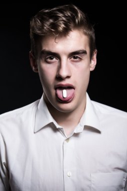 Drugs abuse and addiction tablets.Drug abuse,health danger.Young man under drug influence.Adolescent taking drugs for fun.Young man abusing prescription drugs,painkillers.Party.Ecstasy.