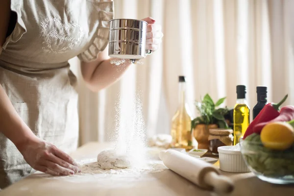 Woman preparing dough basis.Ingredients for baking.Female hands spilling powder on dough.Making dough by female hands.Cooking and baking concept