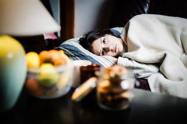 Sick woman in bed,calling in sick,day off from work.Thermometer to check temperature for fever.Vitamins and hot tea in front.Flu.Woman Caught Cold.Virus.Sick woman laying in bed under wool blanket — Stock Photo, Image