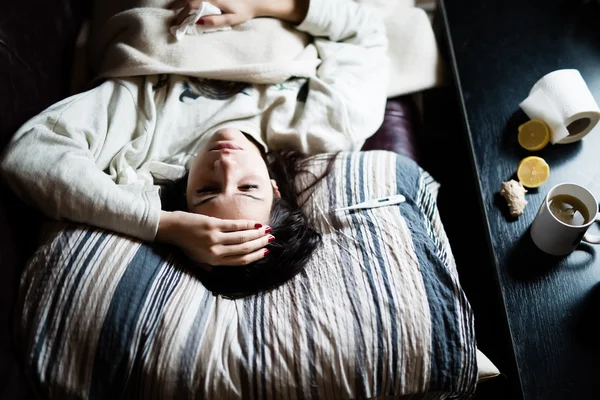 Sick woman in bed,calling in sick,day off from work.Thermometer to check temperature for fever.Vitamins and hot tea in front.Flu.Woman Caught Cold.Virus.Sick woman laying in bed under wool blanket — Stockfoto