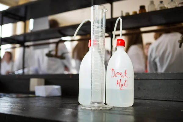 Distilled purified deionised water in plastic bottles with a pump. Measuring graduated cylinder for measuring water volume — Stock Photo, Image