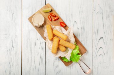 Ahşap tahtada sosisli kızarmış peynir çubukları. Kopyalama Alanıyla Üst Görünüm.