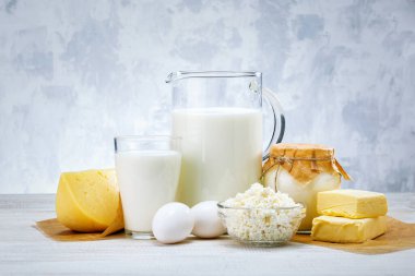 Taze süt ürünleri, süt, peynir, yumurta, yoğurt, ekşi krema ve tereyağı beyaz ahşap masada.
