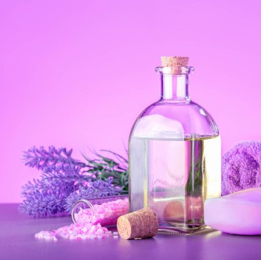 Spa masaj konsepti. Cam şişe lavanta yağı, taze lavanta çiçekleri, deniz tuzu, sabun ve havlu..