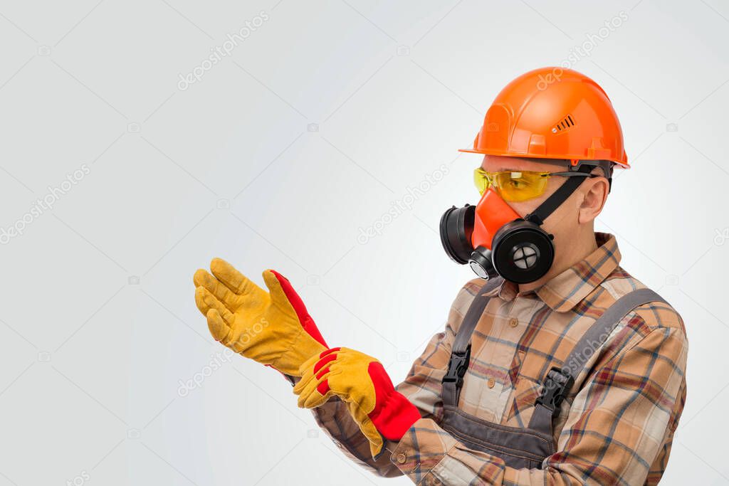 Construction worker putting on protective gloves over gray background. Personal safety equipment.