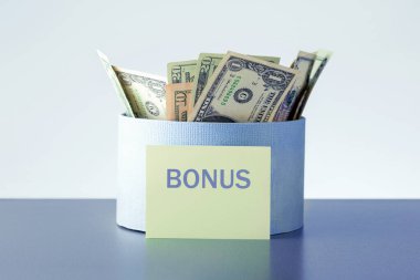 Yıllık bonus konsepti. Gri arka planda para dolu kutu.